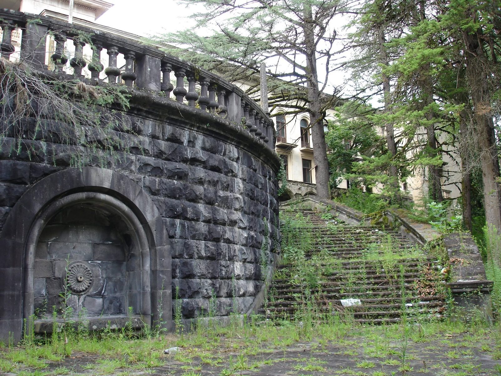 Un mur de pierre avec une niche en arc et des marches qui montent.