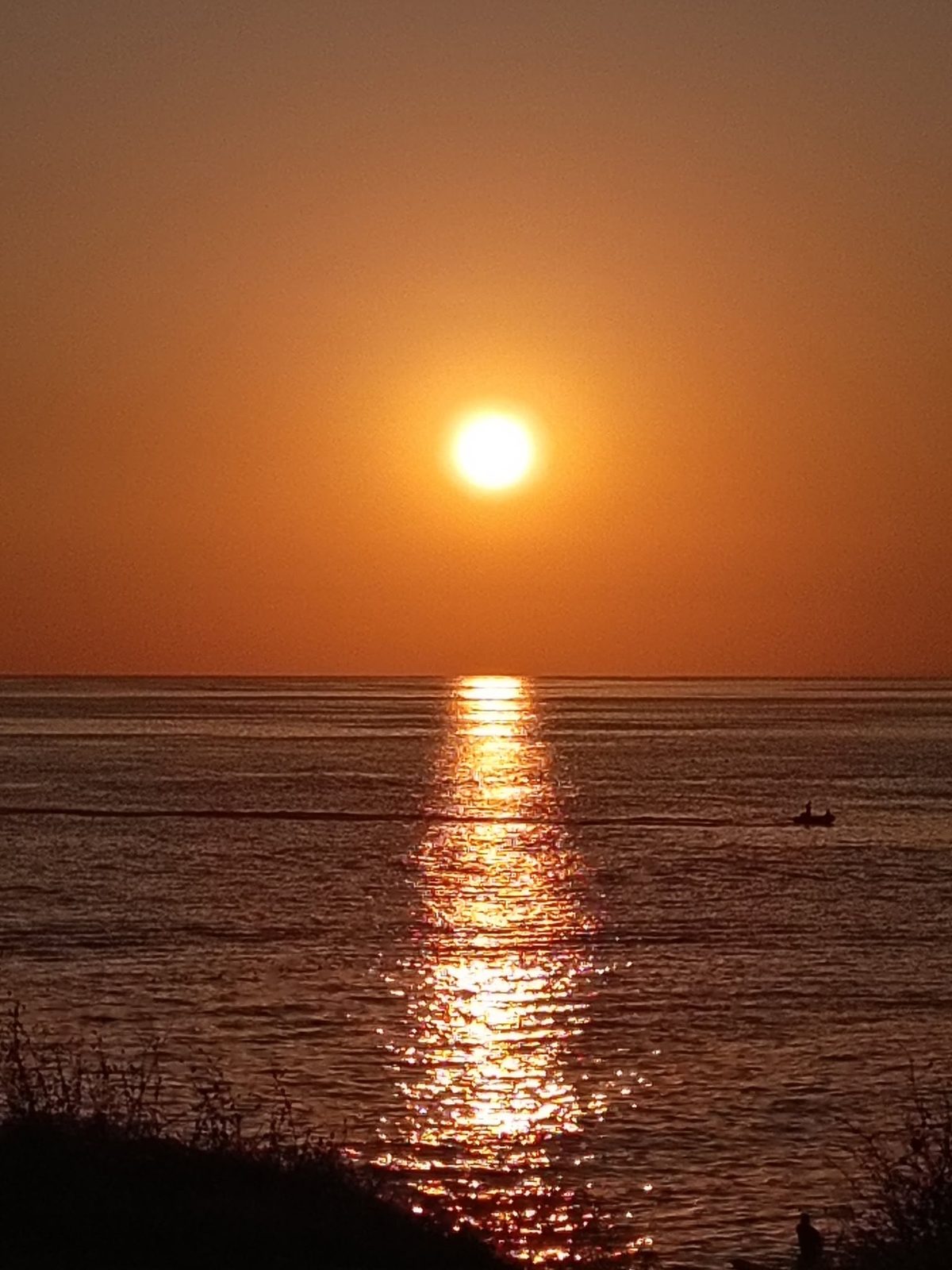 Coucher de soleil sur la mer : le soleil descend vers l'horizon.